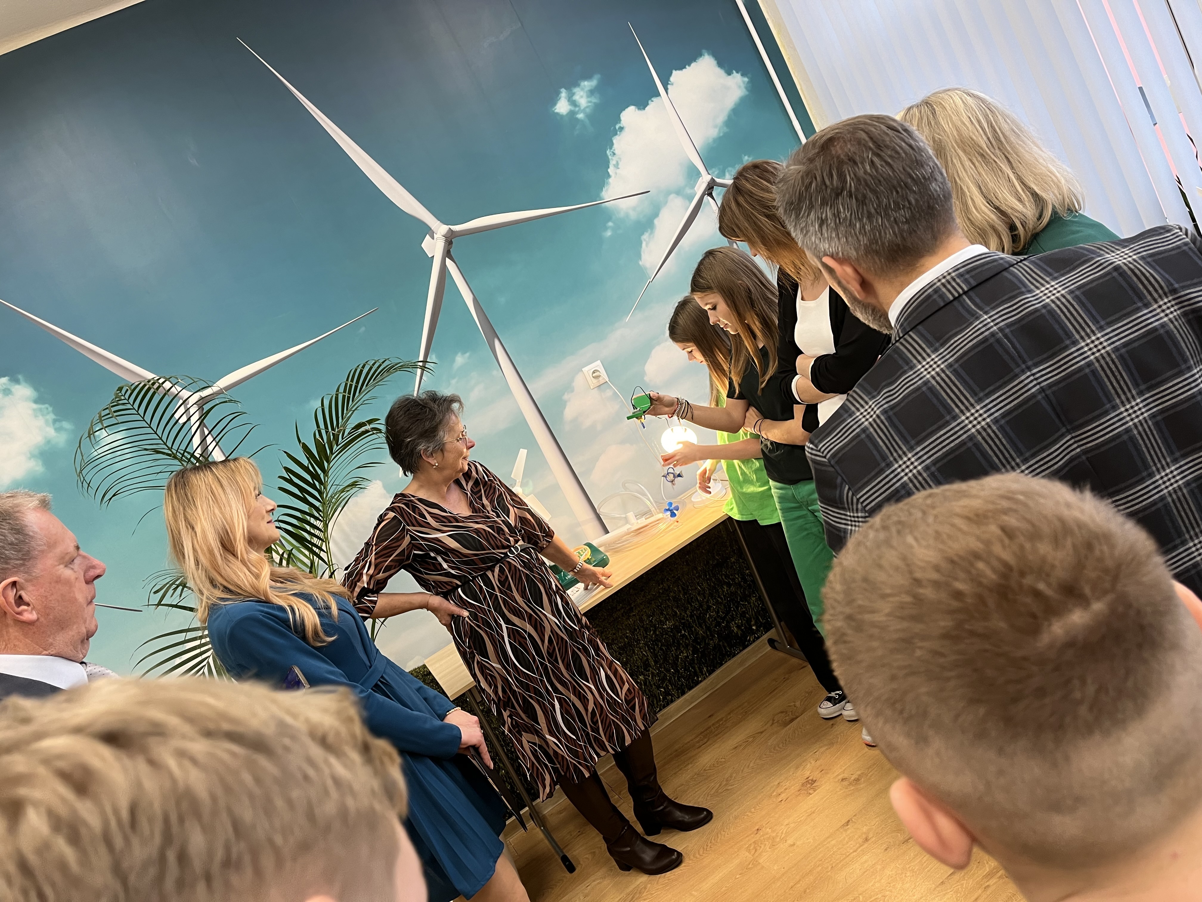 Ogladanie sprzętów w Ekopracowni, w tle fototapeta na której są elektrownie wiatrowe